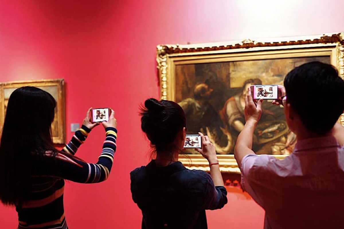 A group photographing an augmented painting in a gallery